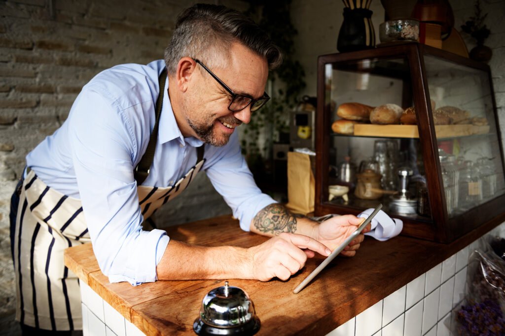 Comerciante usando una tablet en su negocio para consultar un préstamo semanal
