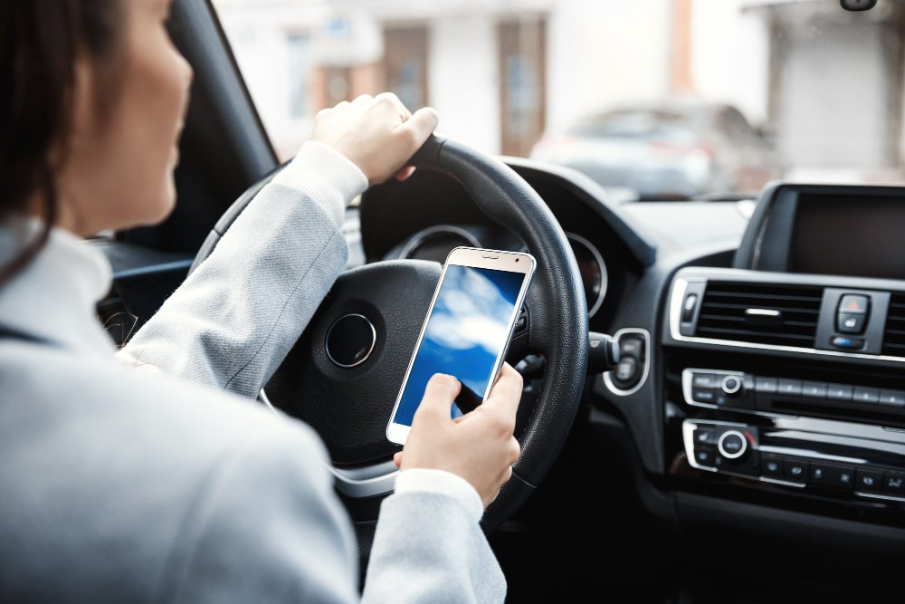 plano recortado de las manos de una mujer sosteniendo el volante y un telefono inteligente